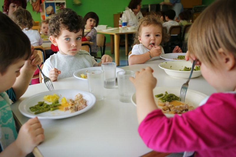 niños y niñas comiendo en el comedor escolar