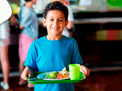 Niño con bandeja de comida en el comerdor escolar